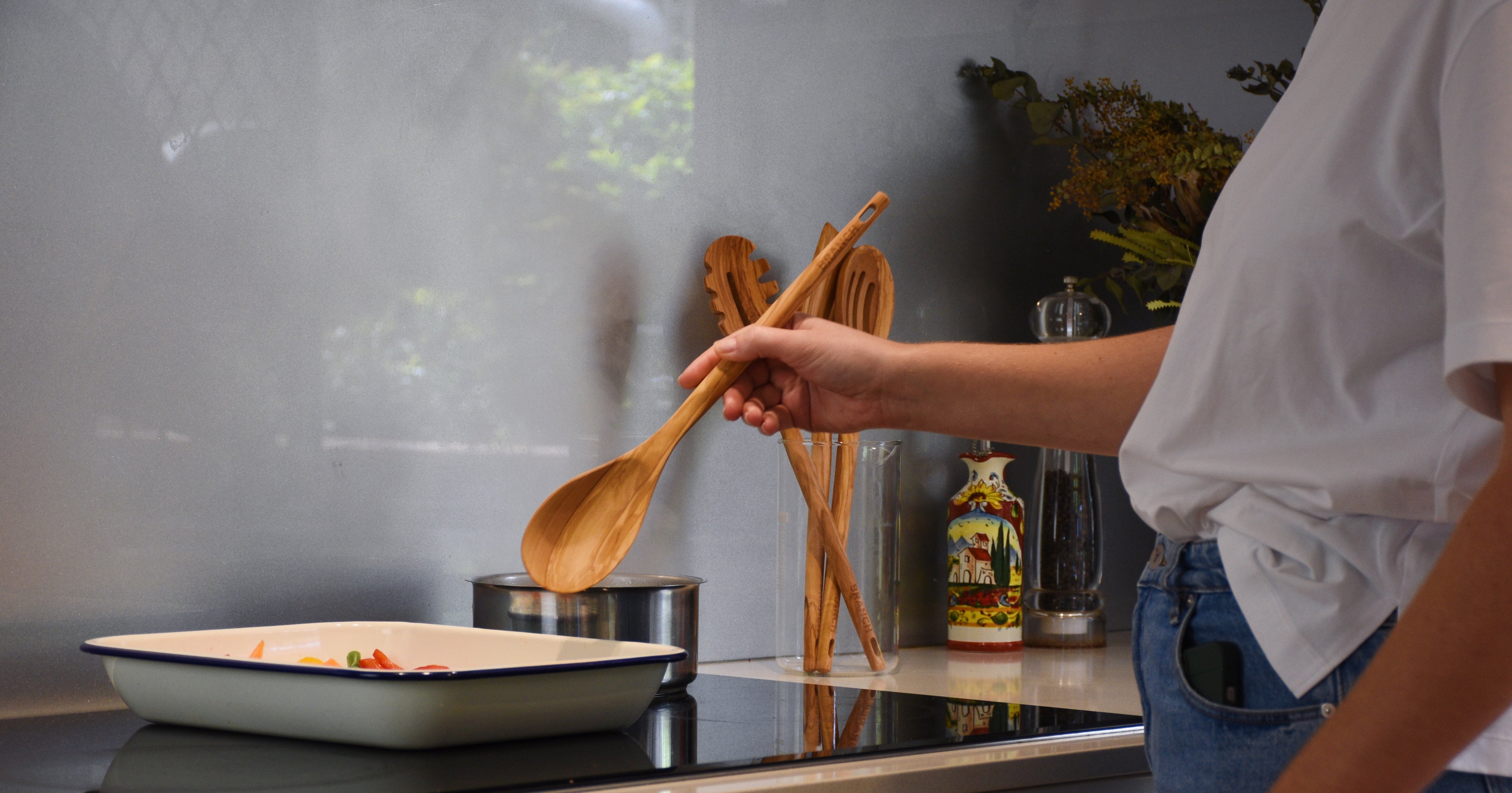 Person stirring a dish with a wooden spoon in a kitchen setting