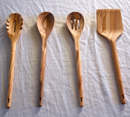 Four wooden cooking utensils on a light fabric background
